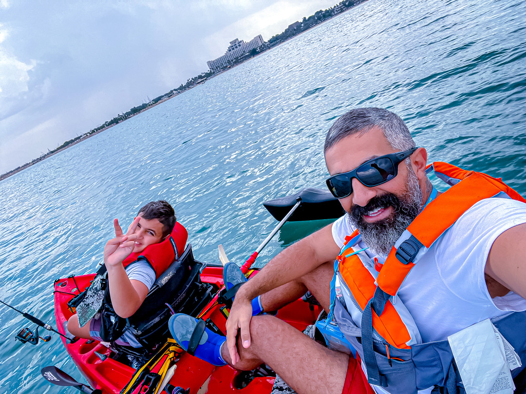 Sanad and his father wearing lifejackets on the double kayak